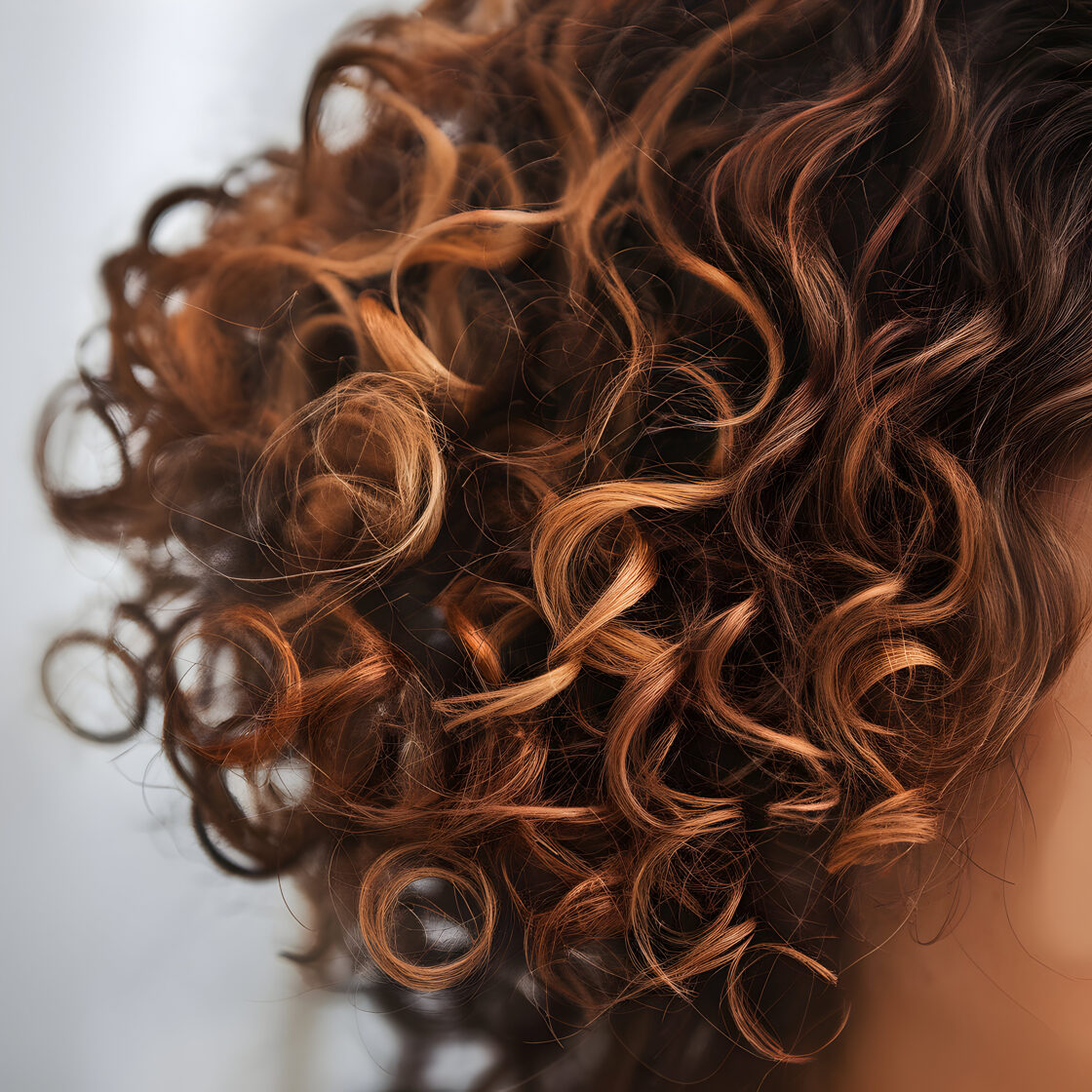 rich-brown-curls-with-auburn-highlights-create-warm-voluminous-texture-against-blurred-background-f.jpg